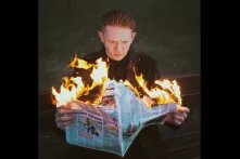 Man holding a burning newspaper