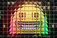 A photographic rendering of a smiling face emoji seen through a refractive glass grid, overlaid with a diagram of a neural network.